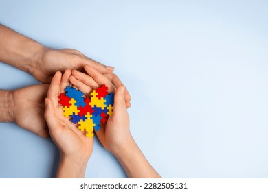 Woman and child hands holding together colorful puzzle heart on light blue background. World autism awareness day, Autism spectrum disorder concept - Powered by Shutterstock