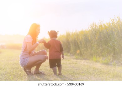 The Woman And Child Holding Hands At Sunset