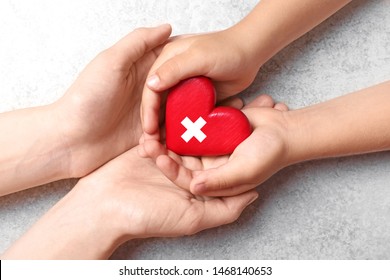 Woman And Child Holding Heart On Light Grey Background, Closeup. Donation Concept