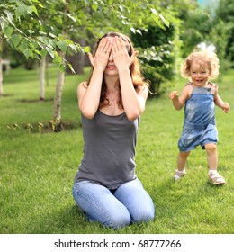 Woman And Child Playing Hide And Seek In Summer Park