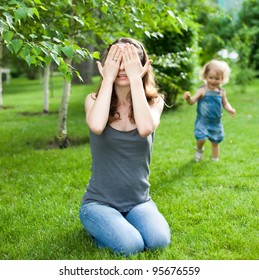 Woman And Child Playing Hide And Seek In Spring Park