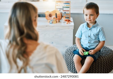 Woman, child and psychology with talking for therapy consultation, development evaluation and progress review. Boy, psychologist and checkup for autism counselling, learning support and assessment - Powered by Shutterstock