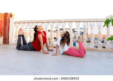 A woman and a child synchronously do warm-up exercises, laugh, practice yoga on the balcony against the backdrop of the city - Powered by Shutterstock