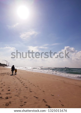 a woman with a child walks along the sandy seashore