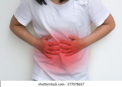 Woman Child's Hands On Her Stomach With Red Spot As Suffering On Stomachache. Girl School Kid  Suffer From Chronic Diarrhea,Digestive Disorders, Stomach Pain,Crohn’s Disease, Irritable Bowel Syndrome