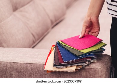 Woman chooses the colors and patterns of upholstery fabrics. Textile industry background. Tissue catalog. Young woman chooses the fabric for new sofa. Fabric samples to upholstery the sofa.