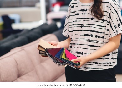 Woman chooses the colors and patterns of upholstery fabrics. Textile industry background. Tissue catalog. Young woman chooses the fabric for new sofa. Fabric samples to upholstery the sofa.