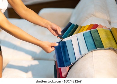 The woman chooses the fabric on the sofa. Textile industry background. Tissue catalog