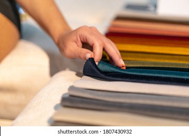 The woman chooses the fabric on the sofa. Textile industry background. Tissue catalog