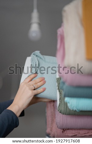 Woman chooses fabric in pile of muslin