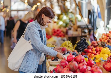 Woman is chooses fruits and vegetables at food market. Reusable eco bag for shopping. Sustainable lifestyle. Eco friendly concept.  - Powered by Shutterstock