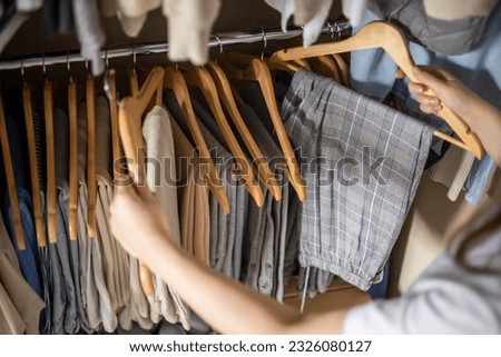 A woman chooses her pants in the closet. The concept of a harmonious capsule wardrobe.