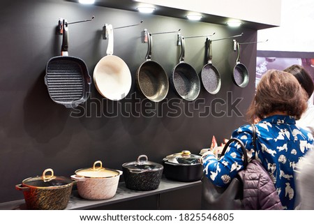 Woman chooses pans in the store household goods