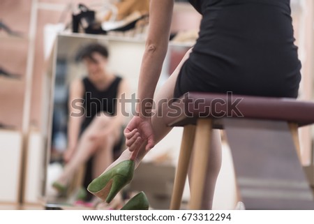 Woman Chooses  Shoes At Fashionable Shop