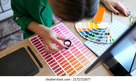 Woman chooses through magnifying glass color and shades on color palette. Choice of color in interior concept