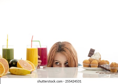 Woman choosing between fruits, smoothie and organic healthy food against sweets, sugar, lots of candies, unhealthy food. Treating your sweets addiction with fruits and vegetables