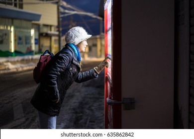Woman choosing beverage on vending machine,Woman choosing drink at Night on road side with snowy ground,Japan vending machine in tokyo,High ISO image.