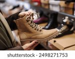 Woman is choosing and buying stylish leather ankle boots in shoe store. Shopping trendy shoes