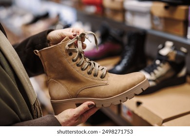 Woman is choosing and buying stylish leather ankle boots in shoe store. Shopping trendy shoes - Powered by Shutterstock