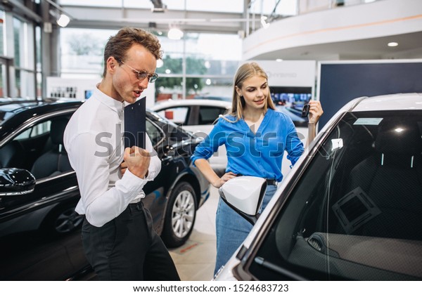 Woman choosing a car in\
a car showroom