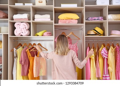 Woman choosing clothes from large wardrobe closet