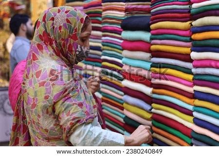 A woman choosing the color of dress fabric in a local market of Lahore, Pakistan.