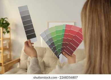 Woman choosing color for wall in room, focus on hands with paint chips. Interior design - Shutterstock ID 2268356807