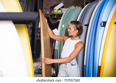 Woman Choosing Colorful Surfboard From Assortment In The Modern Shop