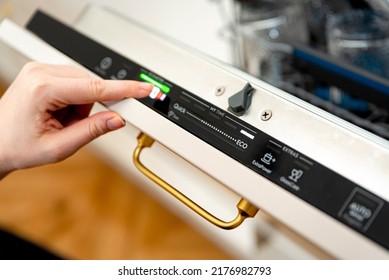 Woman choosing eco mode program on the digital control panel of the dishwasher. Eco cycle of dishwashing machine, energy saving at home concept