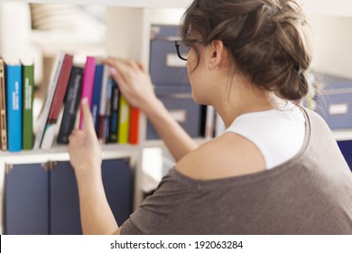 Woman Choosing Favourite Book From Home Library 