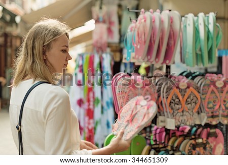 Woman choosing flip-flops for the beach in the market.