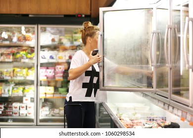 Woman Choosing Frozen Food From A Supermarket Freezer