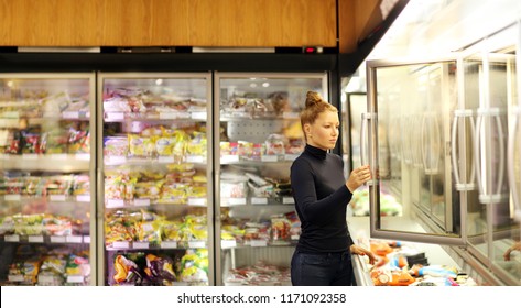 Woman Choosing Frozen Food From A Supermarket Freezer