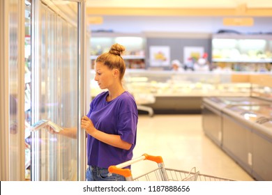 Woman Choosing Frozen Food From A Supermarket Freezer