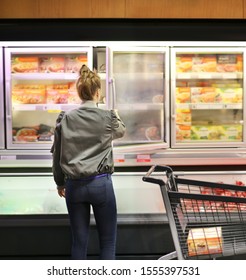 Woman Choosing Frozen Food From A Supermarket Freezer	