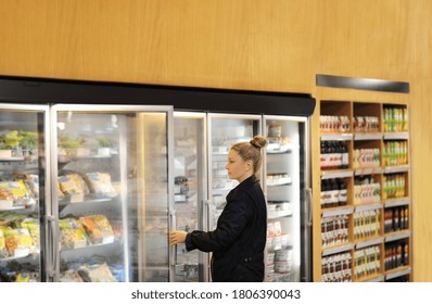 Woman Choosing Frozen Food From A Supermarket Freezer