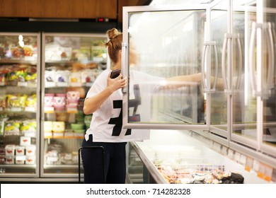 Woman Choosing Frozen Food From A Supermarket Freezer