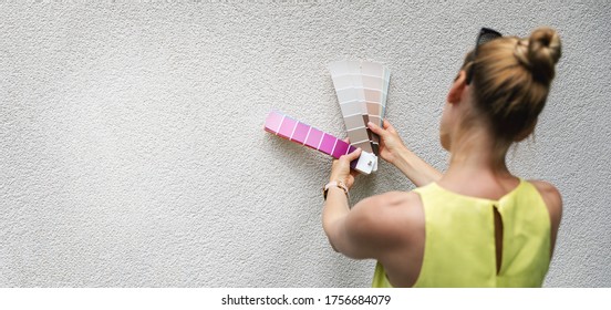 woman choosing paint color from swatch for house stucco exterior facade. copy space