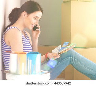 Woman Choosing Paint Colour From Swatch For New Home Sitting On Wooden Floor