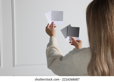 Woman choosing paint shade for wall indoors, focus on hands with color sample cards. Interior design - Shutterstock ID 2216368687