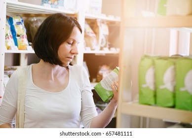 Woman Choosing Products In Ecological Shop With Healthy Food And Reading Product Information On Label