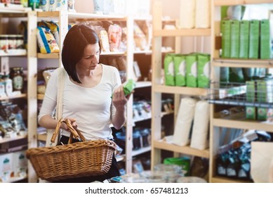 Woman Choosing Products In Ecological Shop With Healthy Food And Reading Product Information On Label