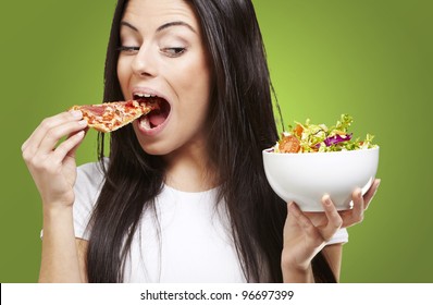 woman choosing a slice of pizza instead of a salad against a green background - Powered by Shutterstock