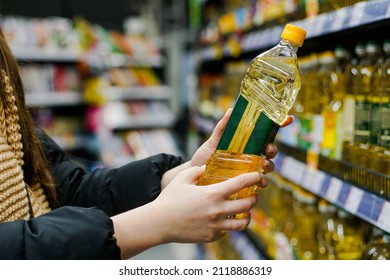 Woman Choosing Sunflower Oil In The Supermarket. Close Up Of Hand Holding Bottle Of Oil At Store.