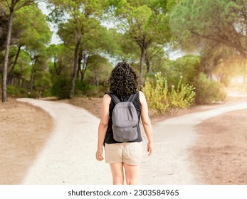Woman choosing to take a light path or a dark path in a forest. Concept of decision making in life.