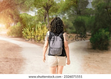 Woman choosing to take a light path or a dark path in a forest. Concept of decision making in life.