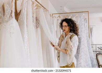 Woman Choosing Wedding Dress In A Showroom. Future Bride Buying A Wedding Gown In A Shop.