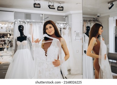 Woman Choosing Wedding Dress In A Showroom. Future Bride Buying A Wedding Gown In A Shop.