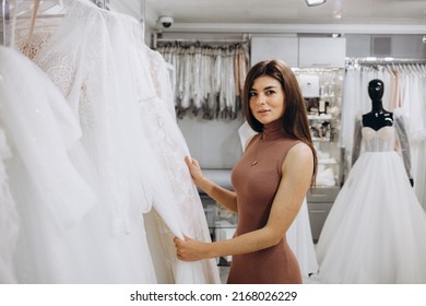 Woman Choosing Wedding Dress In A Showroom. Future Bride Buying A Wedding Gown In A Shop.