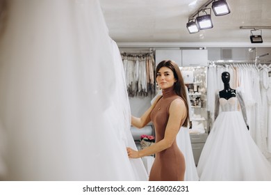 Woman Choosing Wedding Dress In A Showroom. Future Bride Buying A Wedding Gown In A Shop.